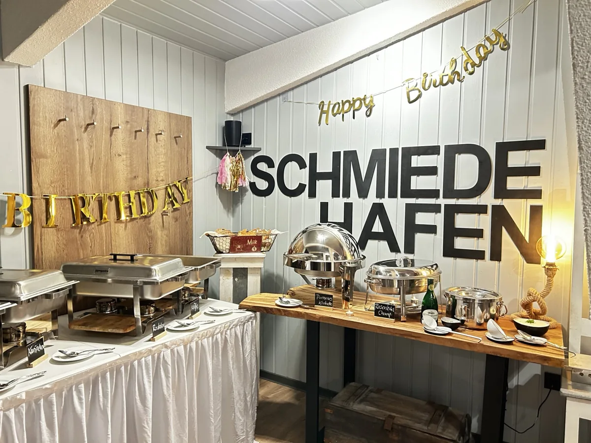 Geburtstagsbuffet unter einem Happy-Birthday-Schriftzug im Schmiedehafen