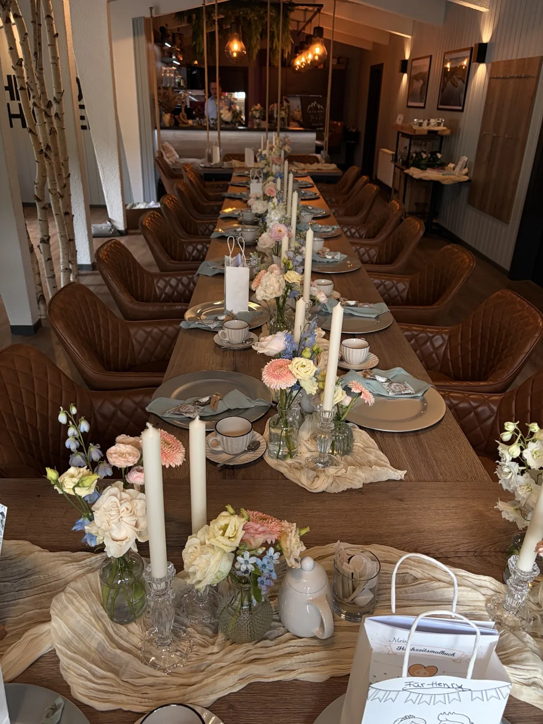 Festliche lange Tafel mit Blumen, Kerzen und gedeckten Plätzen