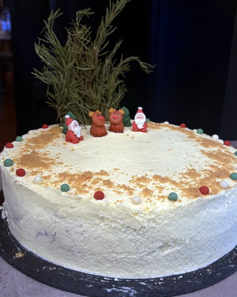 Helle Torte mit kleinen Weihnachtsfiguren und Tannengrün