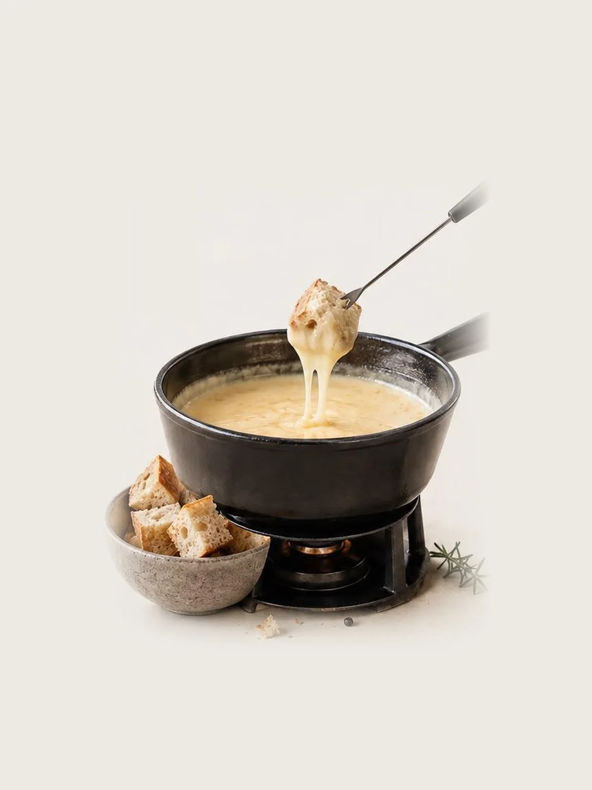 Käsefondue im gusseisernen Topf, ein Brotwürfel wird an der Gabel eingetaucht