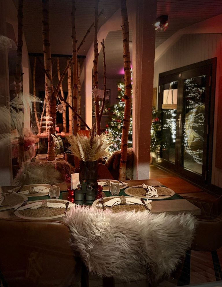 Festlich gedeckter Tisch mit Weihnachtsdekoration und sanfter Beleuchtung.